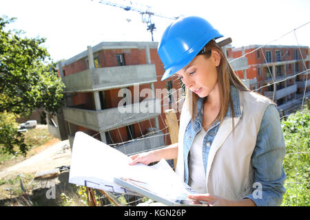 Woman on construction site reading blueprint Stock Photo