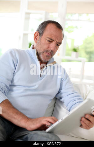 Senior man at home using electronic tablet Stock Photo