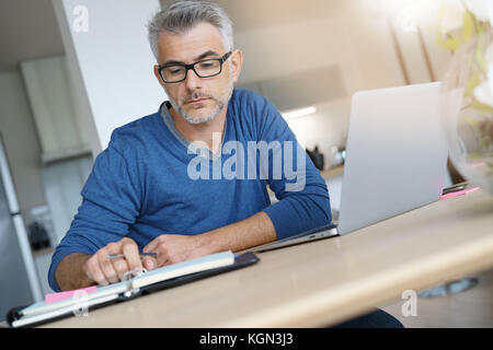 Middle-aged man working from home-office on laptop Stock Photo