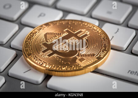Golden Bitcoin on white keyboard closeup - cryptocurrency concept Stock Photo