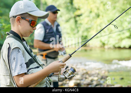 Portrait of young boy learning how to fish with daddy Stock Photo