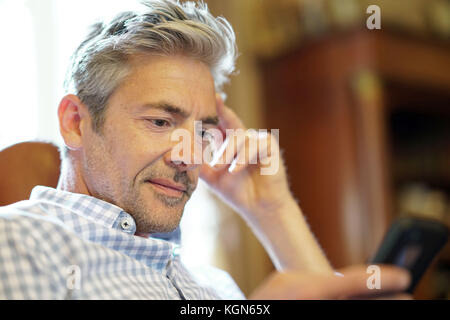 Portrait of mature man reading message on smartphone Stock Photo