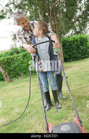 Father and son mowing lawn together Stock Photo