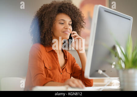 Cheerful businesswoman talking on phone in office Stock Photo