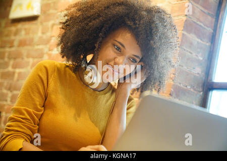 Smiling ethnic girl using laptop in coffee shop Stock Photo