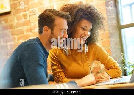 Couple in restaurant connected on internet with laptop Stock Photo