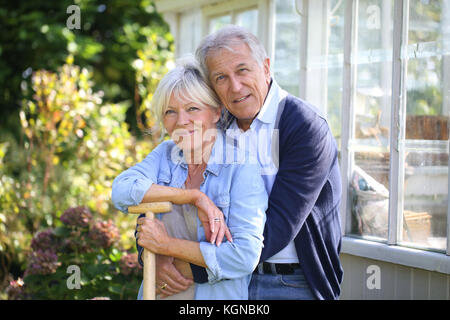 Senior couple standing by greenhouse in garden Stock Photo