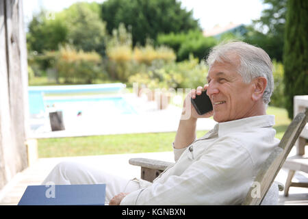 Senior man relaxing in long chair and using telephone Stock Photo