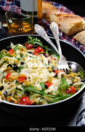 Pasta with crushed olives and cherry tomatoes, arugula. Vertical shot. Stock Photo