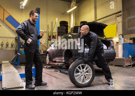 auto mechanics changing car tires at workshop Stock Photo