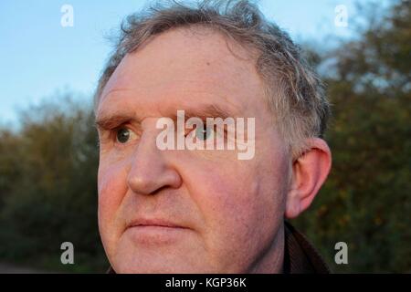Close up face middle aged man looking into evening sun at wildfowl Stock Photo