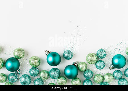 Beautiful, bright, modern, blue and green Christmas holiday ornaments decorations with sparkling glitter on white background. Horizontal border. Stock Photo