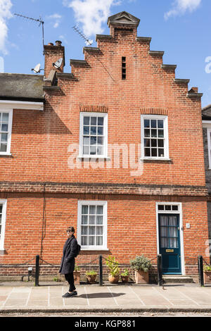 Hipster woman standing on the pavement in front of a Victorian Edwardian restored house in London, UK Stock Photo