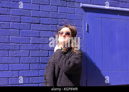 A woman wearing sunglasses standing in front of a wall photo