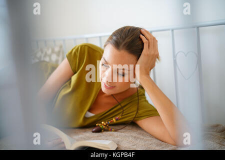 Young woman relaxing in couch and reading book Stock Photo