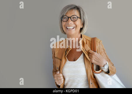 Modern mature woman standing on grey background Stock Photo