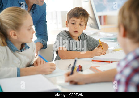 Kids writing notes in classroom Stock Photo