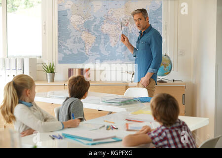 Teacher standing in classroom, kids attending geography lesson Stock Photo