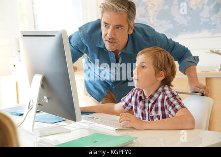 Schoolboy in computer lab with teacher helping Stock Photo - Alamy
