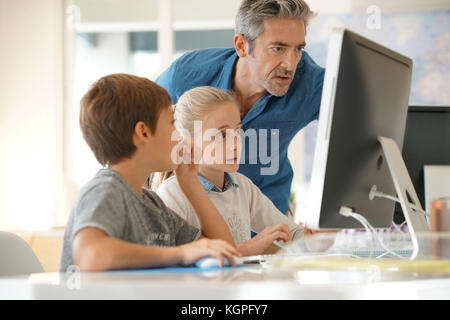 Schoolboy in computer lab with teacher helping Stock Photo - Alamy