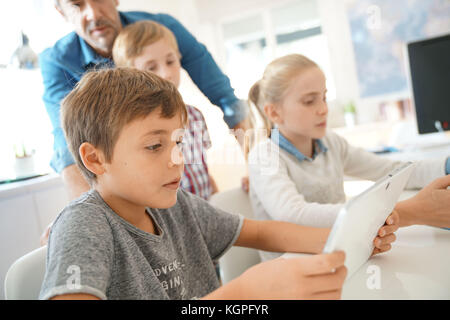 Kids in classroom learning with digital tablet Stock Photo