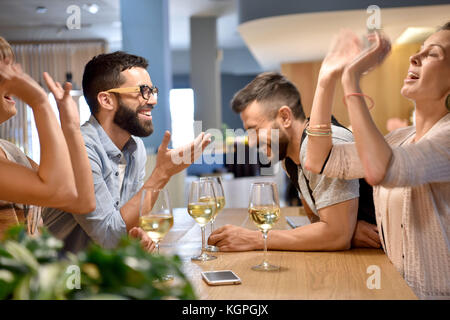 Friends in bar cheering with wine glasses Stock Photo