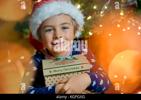 Portrait of cute little boy holding Christmas present Stock Photo
