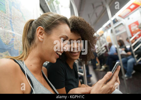 Girls in metro train using smartphone Stock Photo