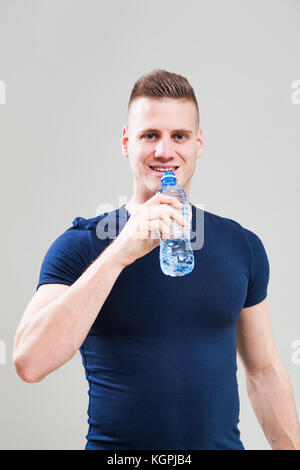 Studio shot image of young sporty man who is drinking water. Stock Photo