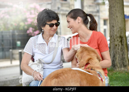 Blind woman and home carer relaxing on bench Stock Photo