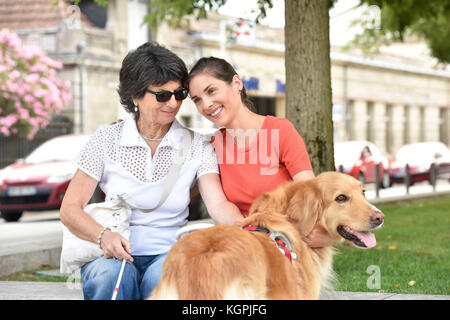 Blind woman and homecarer relaxing on bench Stock Photo