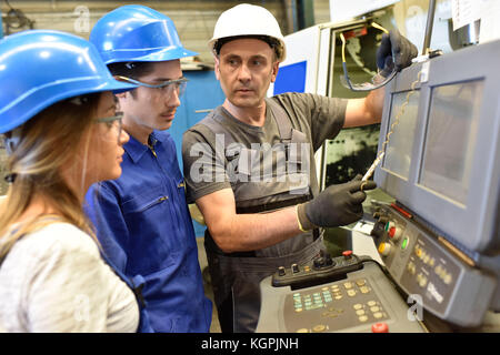 Metalworker with training people using electronic machine Stock Photo