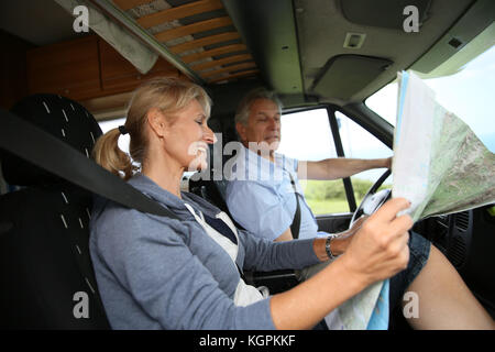 Senior couple riding camper and reading road map Stock Photo