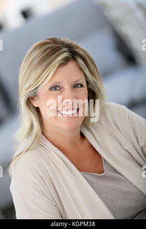 Beautiful 40-year-old woman at home with earphones on, drinking herbal