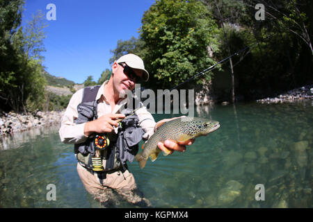 Fly fisherman holding fario trout recently caught Stock Photo