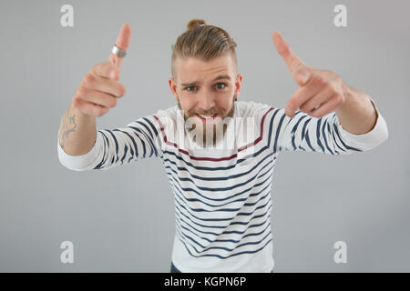 Portrait of trendy guy pointing hands towards calmra Stock Photo