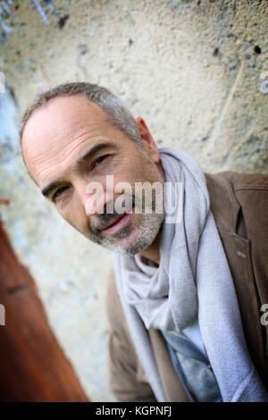Casual senior man leaning against wall Stock Photo