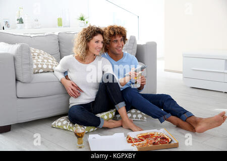 Cheerful couple at home having pizza in font of TV Stock Photo