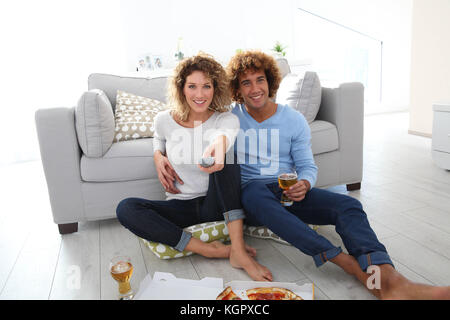 Cheerful couple at home having pizza in font of TV Stock Photo