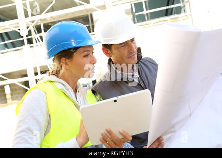 Engineers on building site checking plans Stock Photo