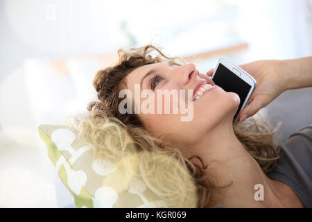 Woman talking on smartphone laid in sofa Stock Photo