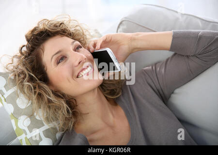 Woman talking on smartphone laid in sofa Stock Photo - Alamy