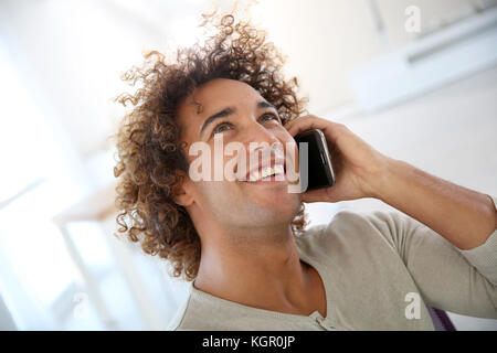 Smiling man in office talking on mobile phone Stock Photo