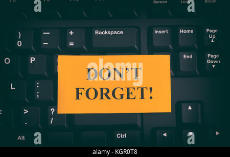 Yellow paper note on black keyboard with writing Don't Forget! Close up. Stock Photo