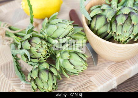 Two artichoke bouquets on kitchen table among some kitchen items. Top view. Stock Photo