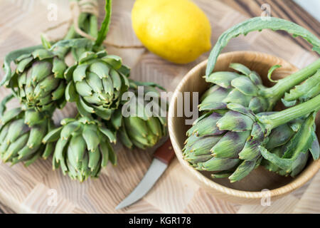 Two artichoke bouquets on kitchen table among some kitchen items. Top view. Stock Photo