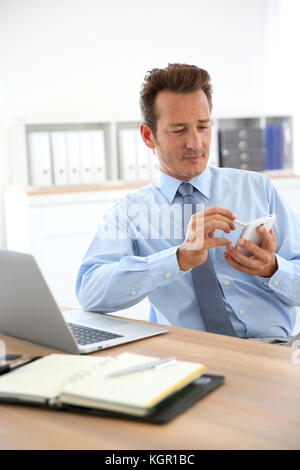 Businessman using smartphone in office Stock Photo