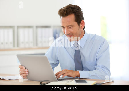 Handsome businessman in office working on laptop Stock Photo