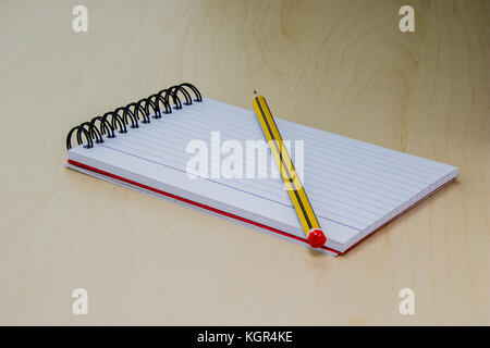 Pencil and notepad on the light wooden table surface. Stock Photo