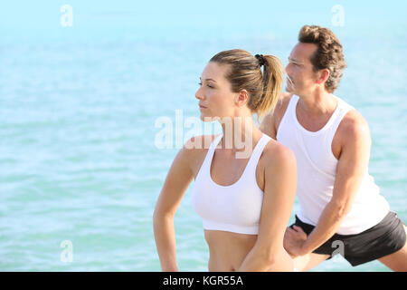 Couple doing yoga and relaxation exercises by the sea Stock Photo